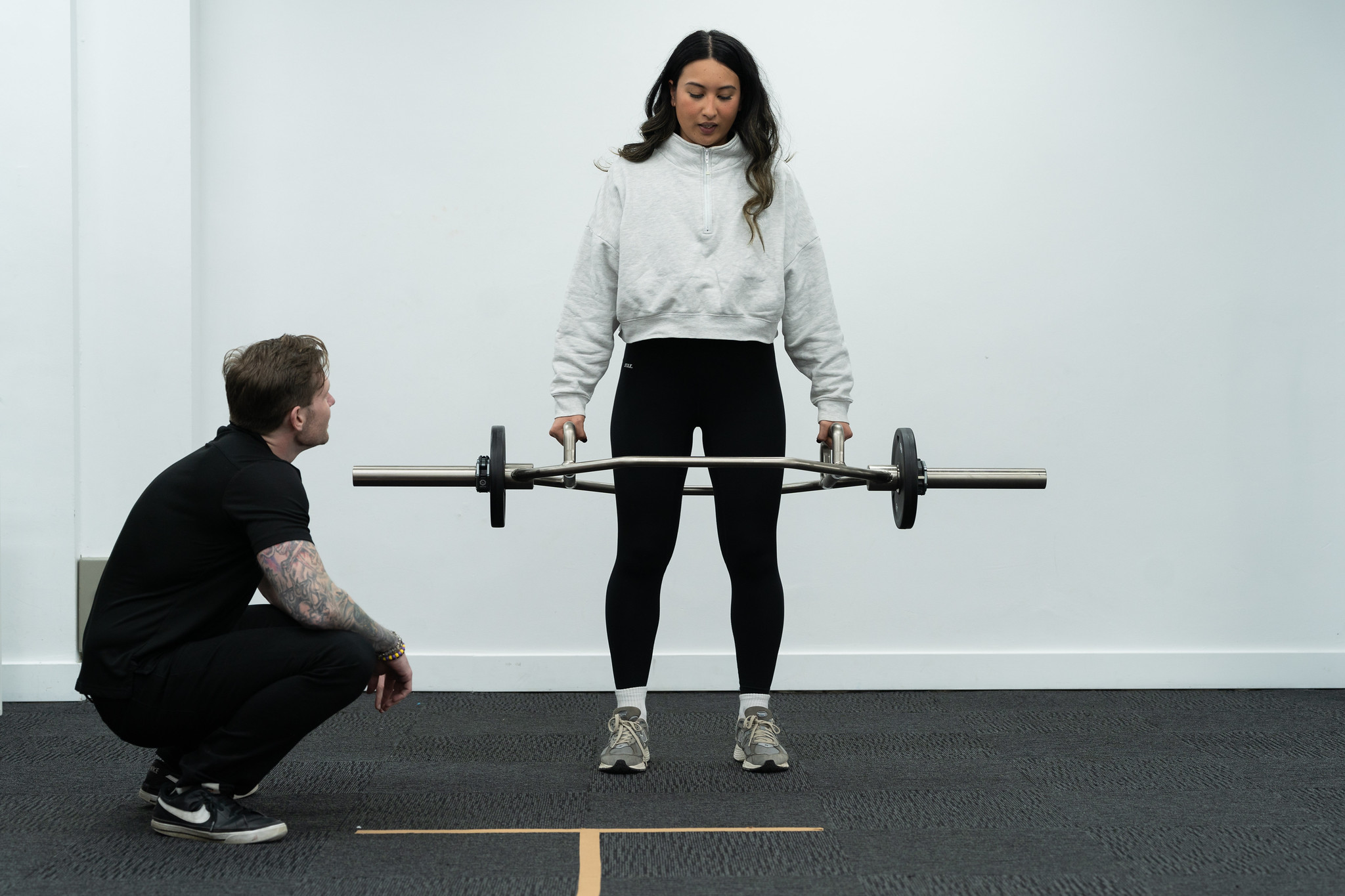 Woman lifting weight with trainer